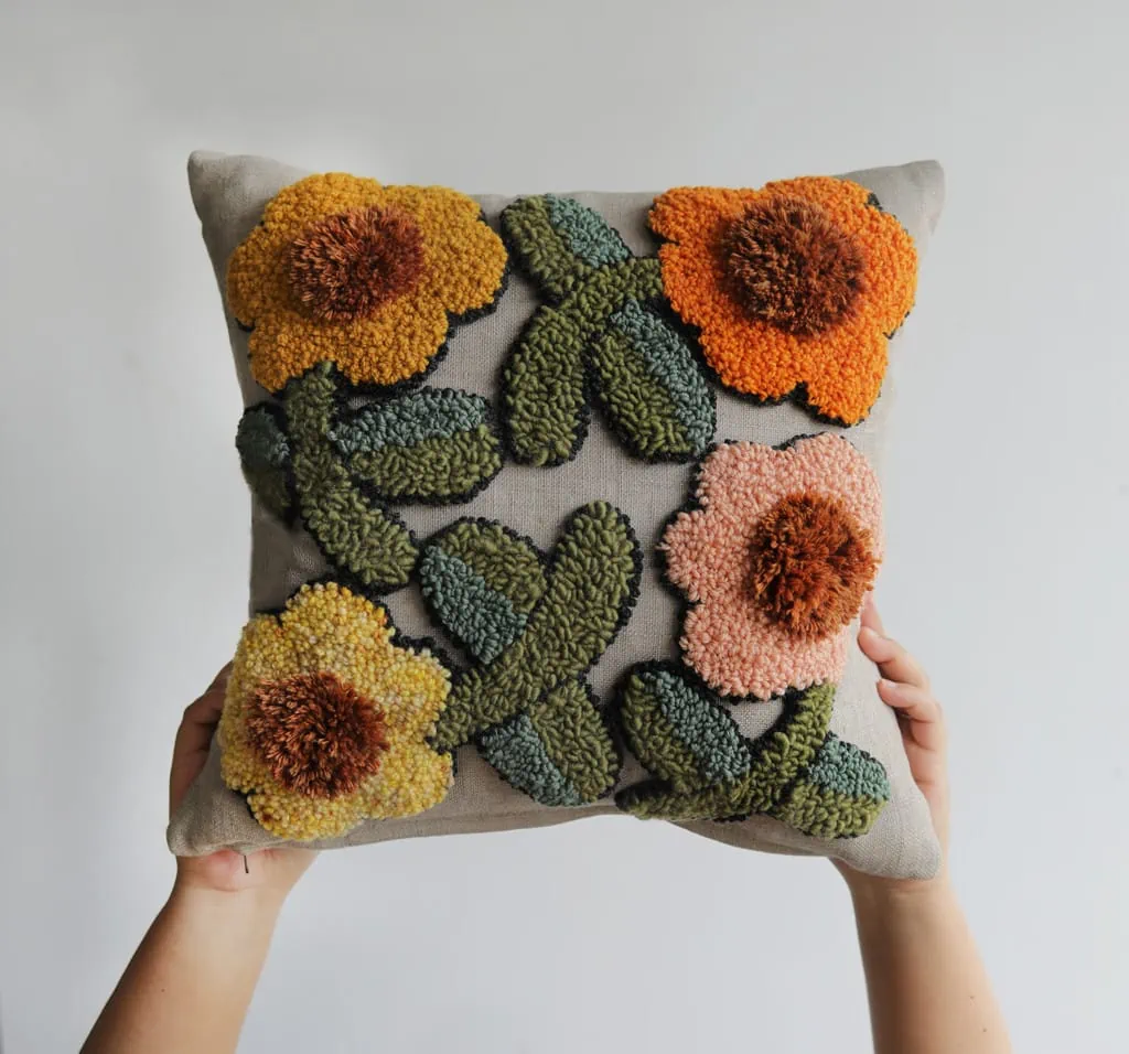 floral punch needle pillow in warm oranges, pinks, yellows, and greens.