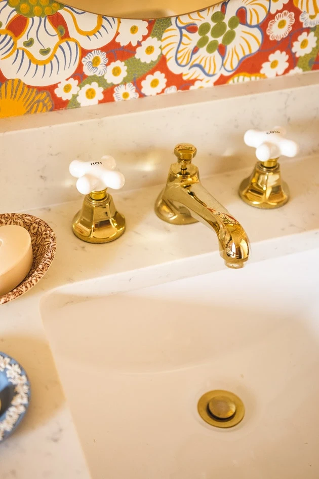 gold faucet on a marble countertop. The handles are ceramic.