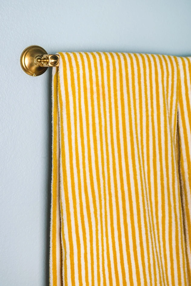 A yellow striped towel hanging on a brass towel rack.