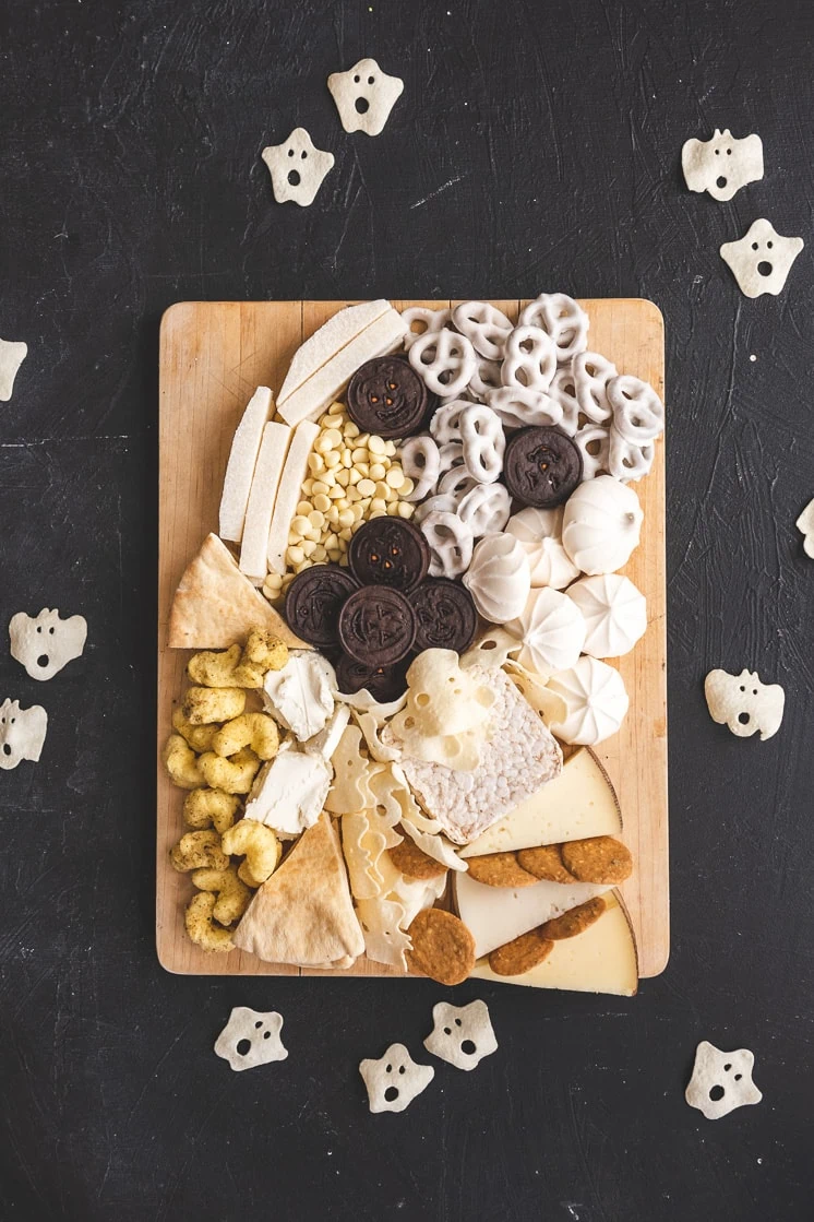 A ghost-shaped halloween snack board on a black background.