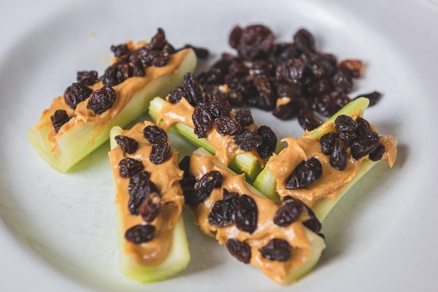 Ants on a log (celery with peanut butter and raisins) on a white plate