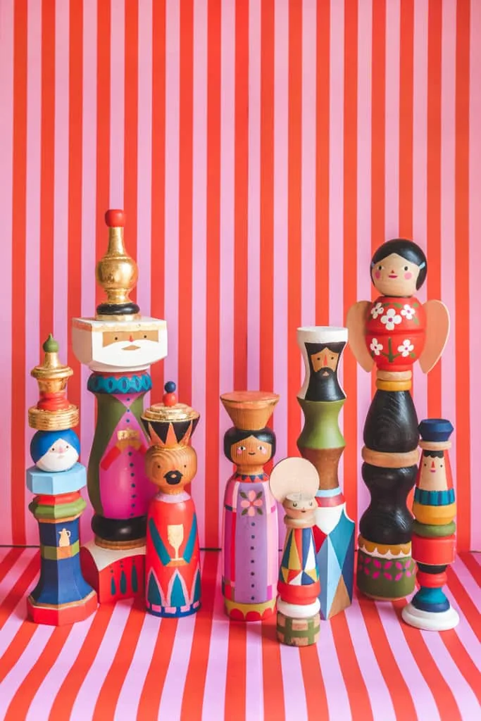 Midcentury painted heirloom nativity figures against a pink and red striped background.