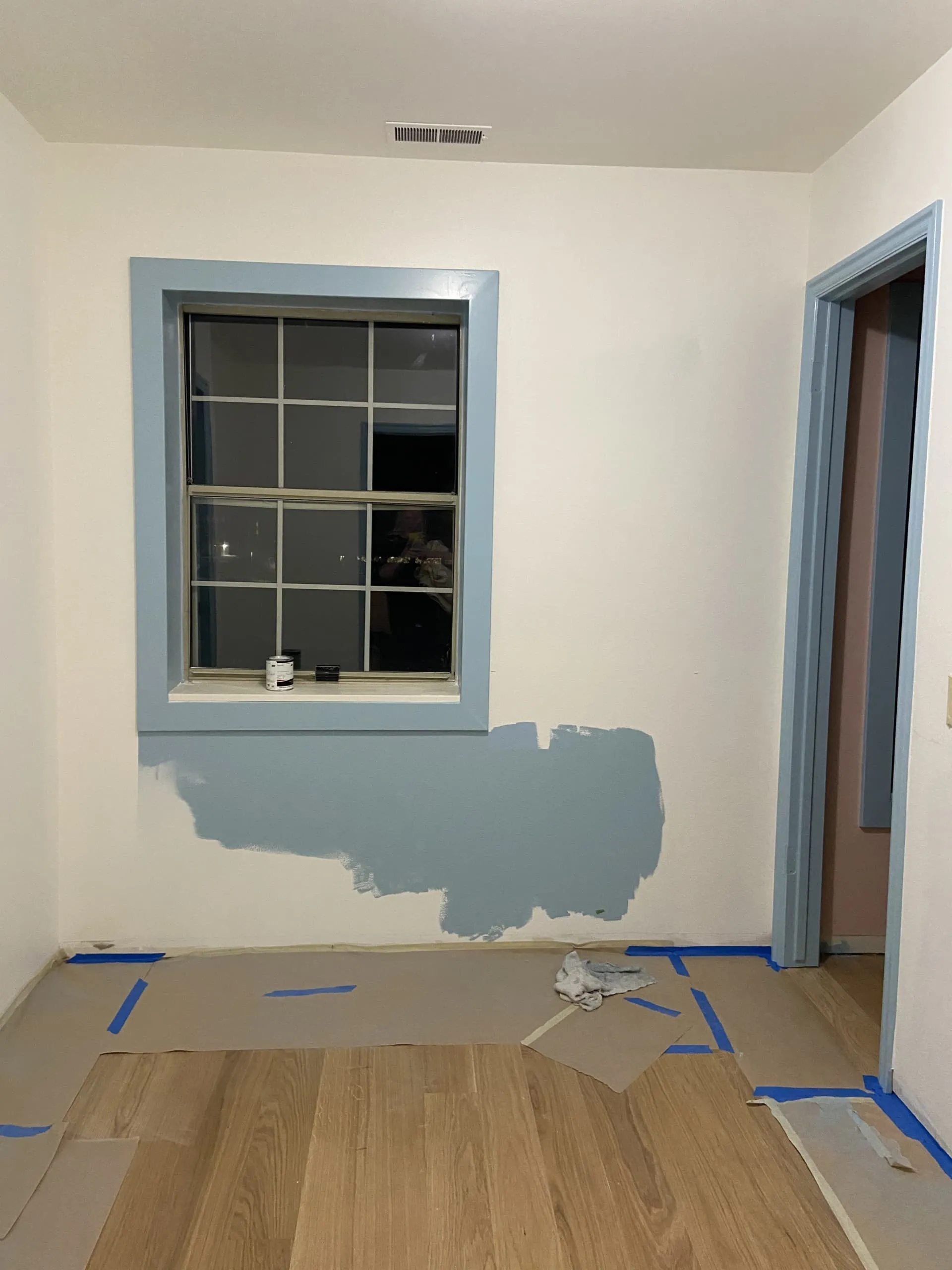 Photo of an interior with wooden floors. The walls are mostly white, but there's some blue paint around the trim and the bottom half of the walls.
