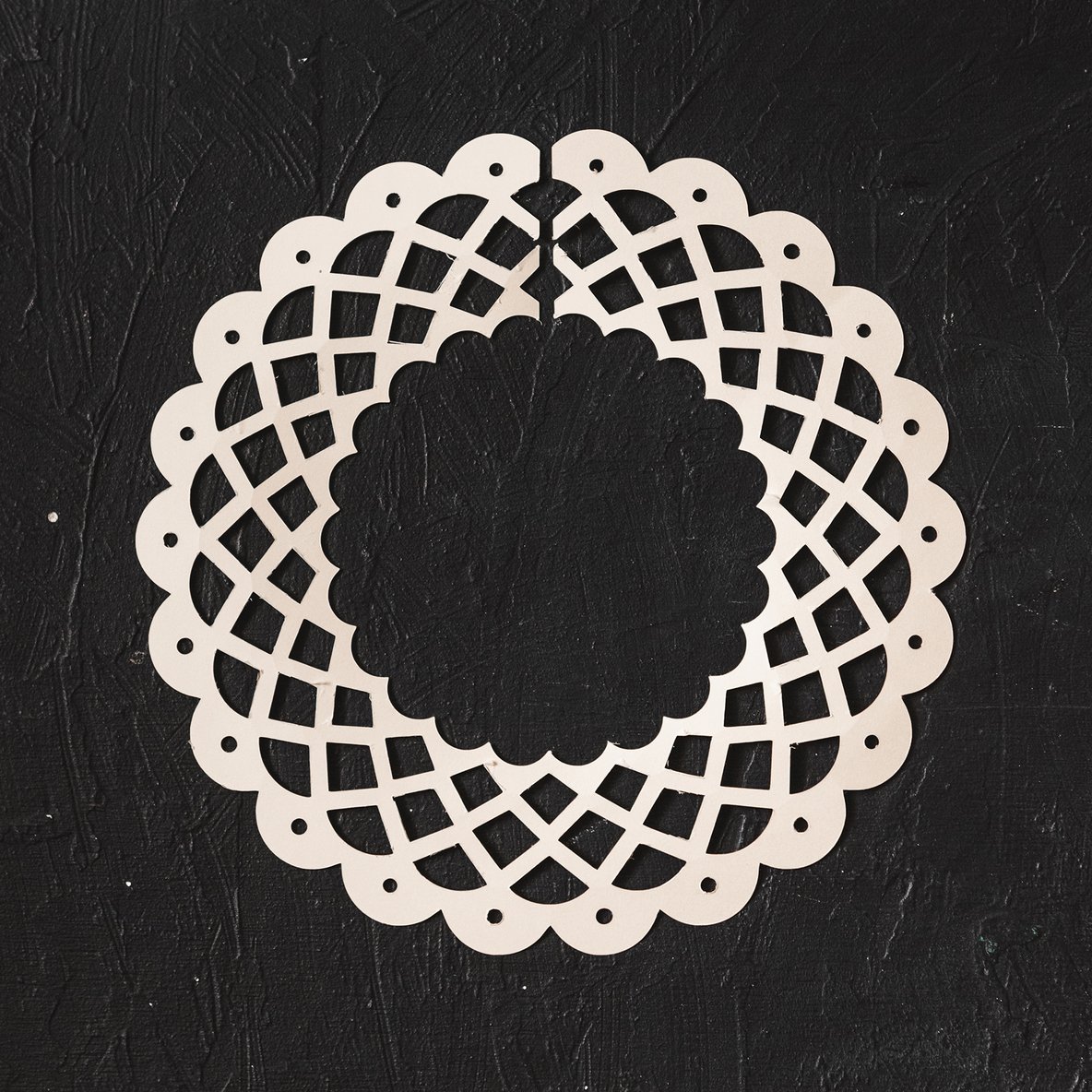 A white paper lace collar on a black background.