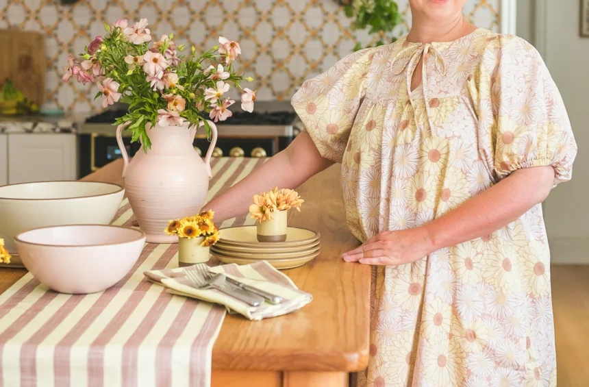woman in kitchen in floral dress with wooden table and table setting