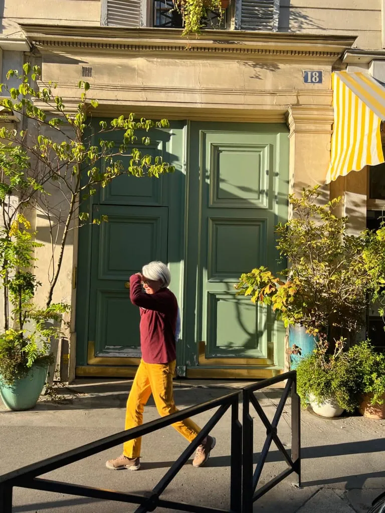 Parisian man walking in front of a green door in Paris 