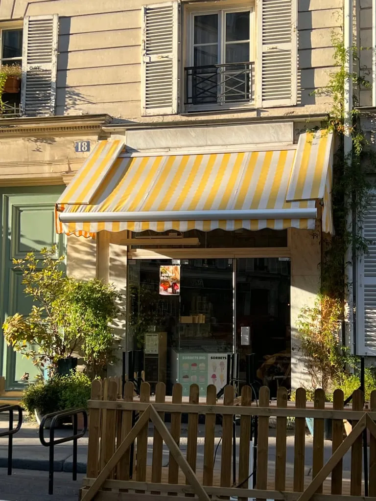 green door with yellow stripe awnings on a cafe in Paris 